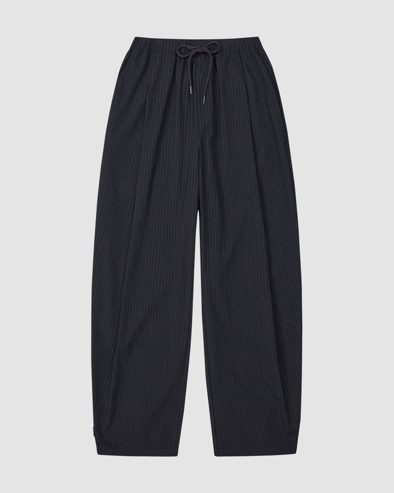 The Sundae School KIKI DRAWSTRING SLACKS are wide-leg, dark navy pinstripe sweatpants with a relaxed barrel leg and elastic drawstring waist, shown laid flat on a light gray background.