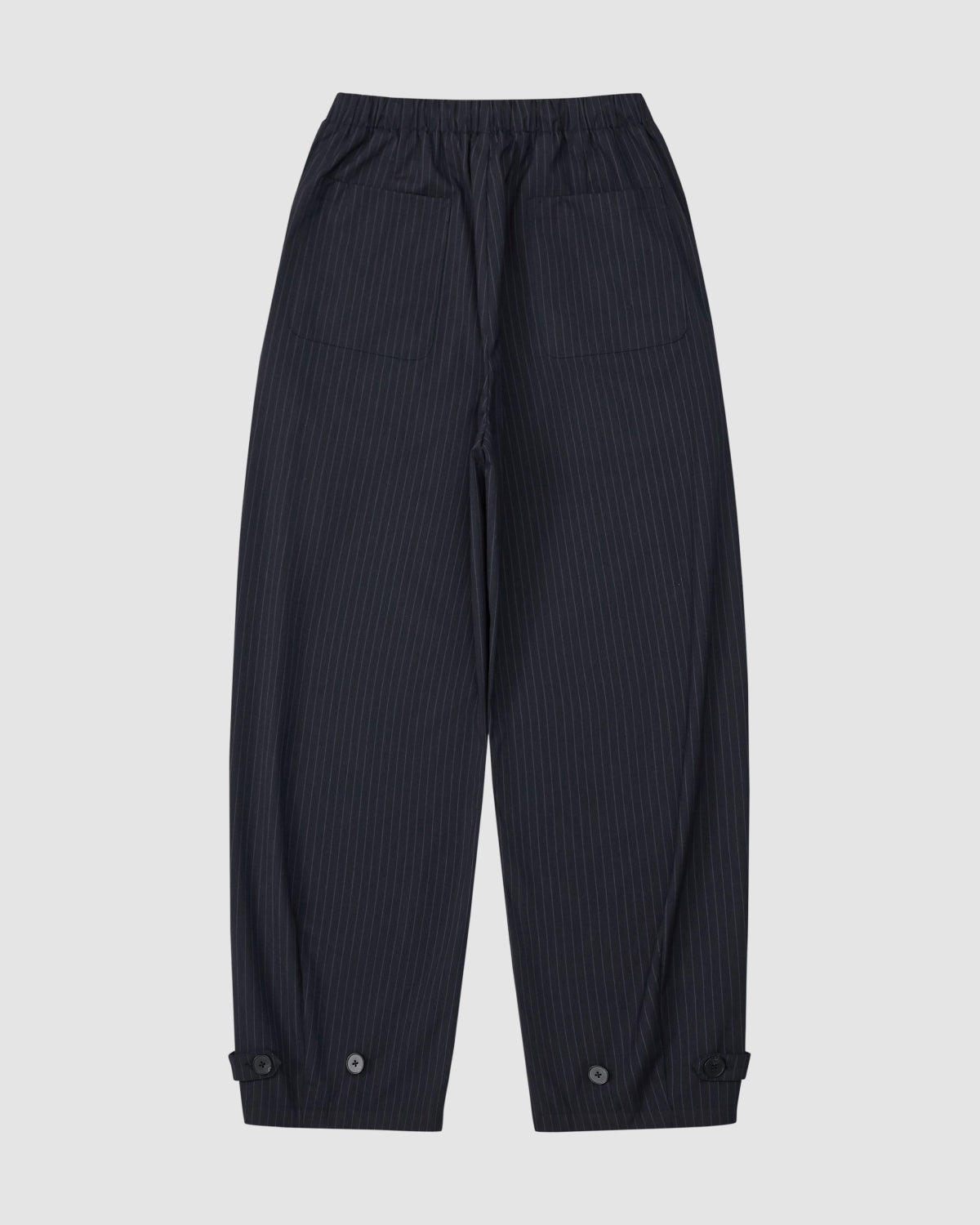 The Sundae School KIKI DRAWSTRING SLACKS are dark navy pinstripe sweatpants with an elastic drawstring waist, front patch pockets, buttoned cuff tabs, and a relaxed barrel leg. Shown laid flat on a light background.