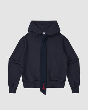 The NAVY KNIT TIE HOODIE by Sundae School is a heavyweight brushed cotton hoodie in navy, featuring a matching knit tie with red embroidery, ribbed cuffs and waistband, shown against a light gray background.