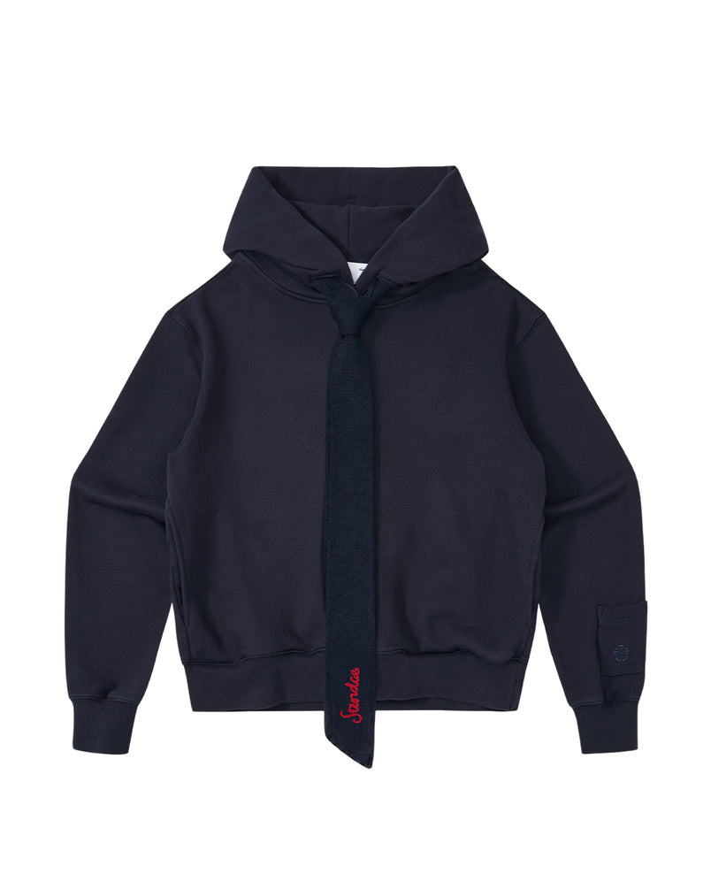 The Sundae School NAVY KNIT TIE HOODIE is a unisex heavyweight hoodie in navy blue, made from brushed cotton for enhanced comfort and style. It features a matching attached tie and a subtle red embroidered accent near the bottom of the tie.