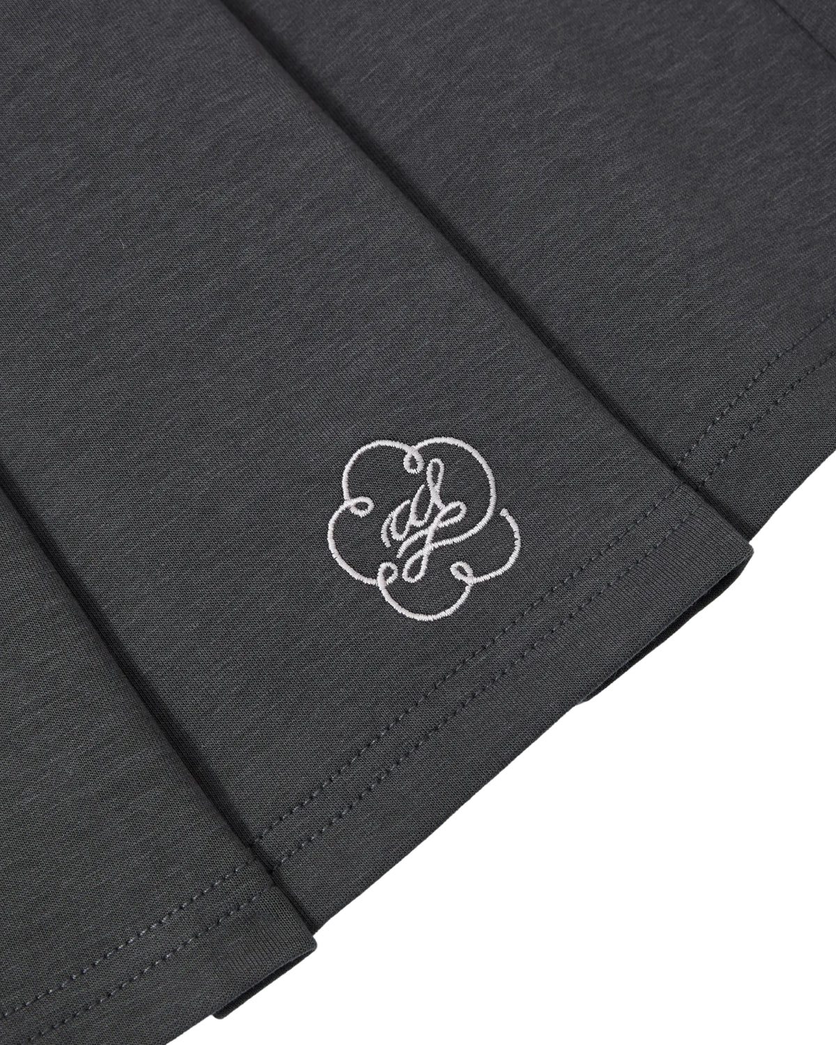 Close-up of the embroidered white flower logo on the Sundae School CHARCOAL KONA MIDI SKIRT.