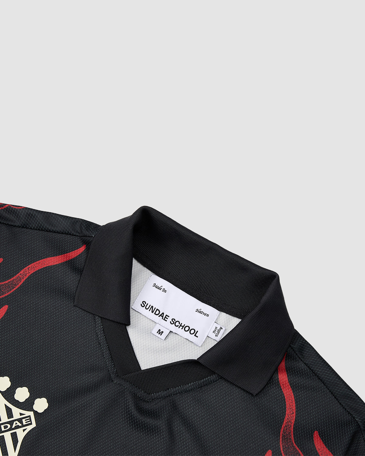 A close-up of the KOREATOWN FOOTBALL JERSEY by Sundae School, size M—black with red flame designs and a white Sundae School collar label. A partial gold graphic inspired by custom Korean art appears on the left, adding K-Town fashion flair.