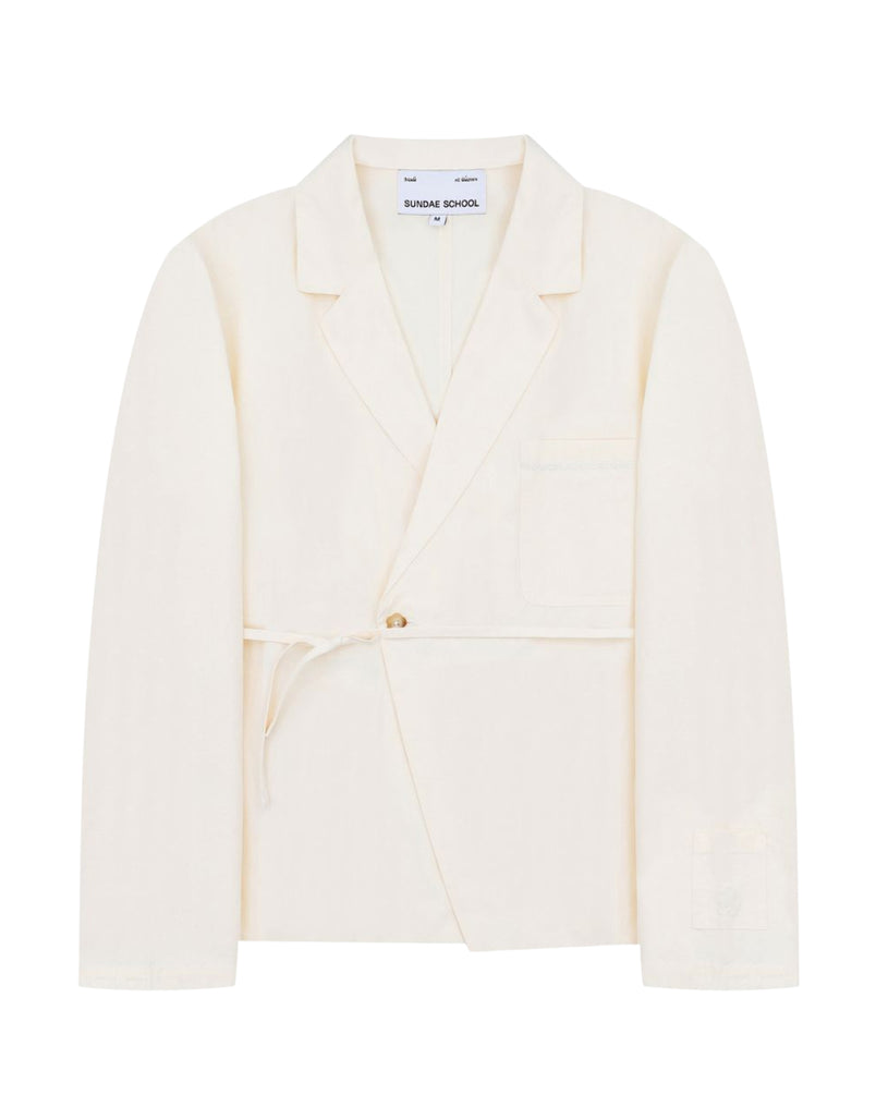 An ivory linen “Gorum Blazer” by Sundae School, featuring a single button closure, tied fabric belt, notched lapels, and a chest pocket. The label inside reads Sundae School.