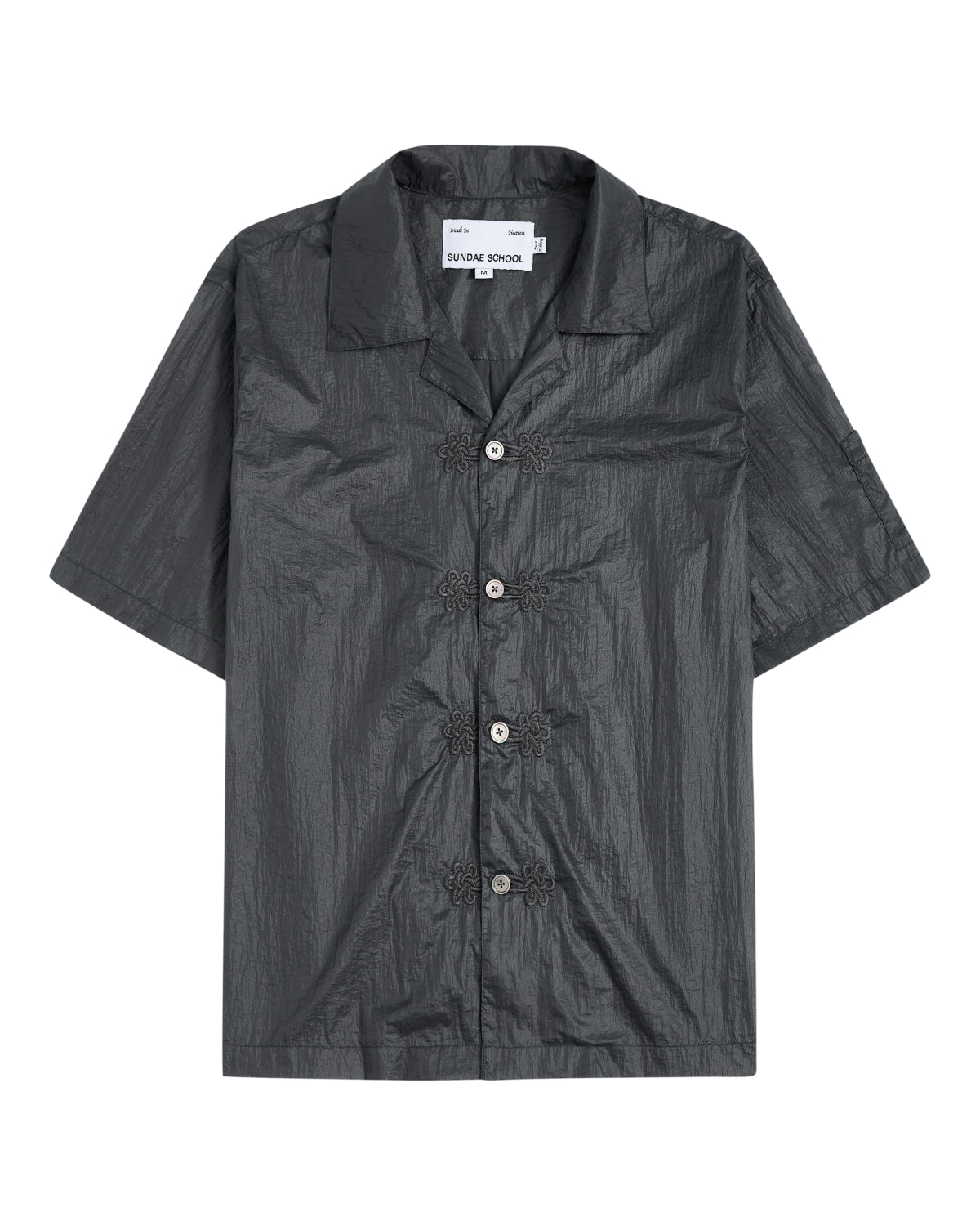 The MAEHWA EMBROIDERED SHEER SHIRT by Sundae School is a short-sleeve, dark gray, collared button-up featuring a crinkled texture and distinctive flower-shaped black buttons down the front—this unisex going-out shirt effortlessly elevates any look with its unique edge.