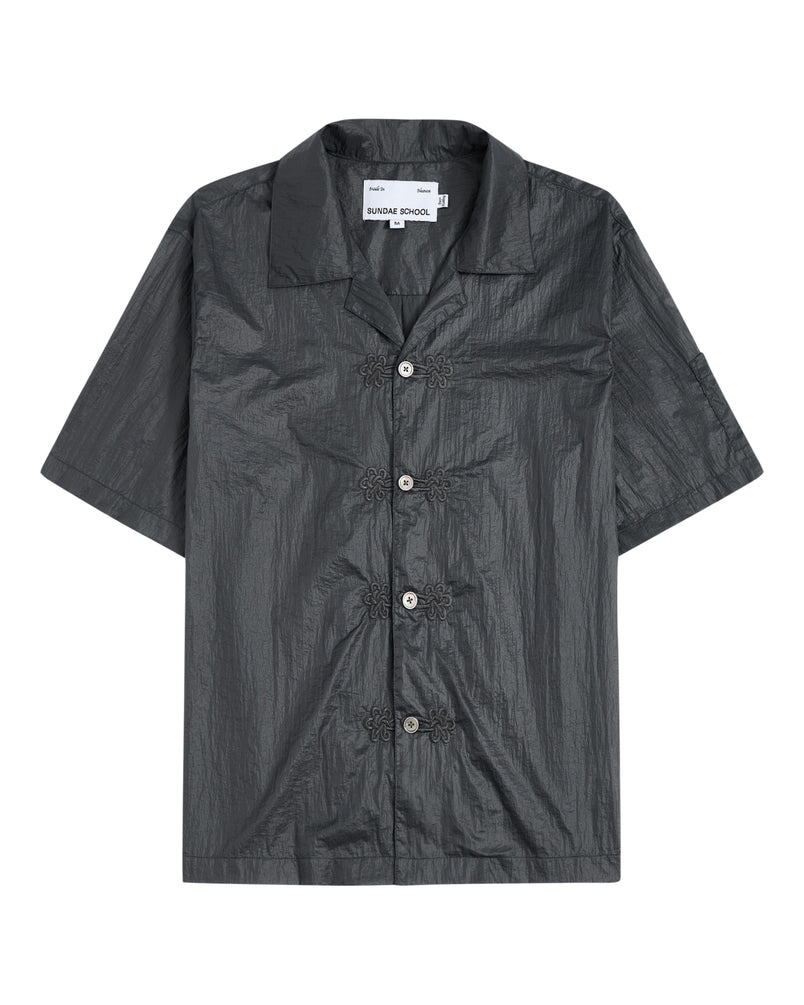 The MAEHWA EMBROIDERED SHEER SHIRT by Sundae School is a short-sleeve, dark gray, collared button-up featuring a crinkled texture and distinctive flower-shaped black buttons down the front—this unisex going-out shirt effortlessly elevates any look with its unique edge.