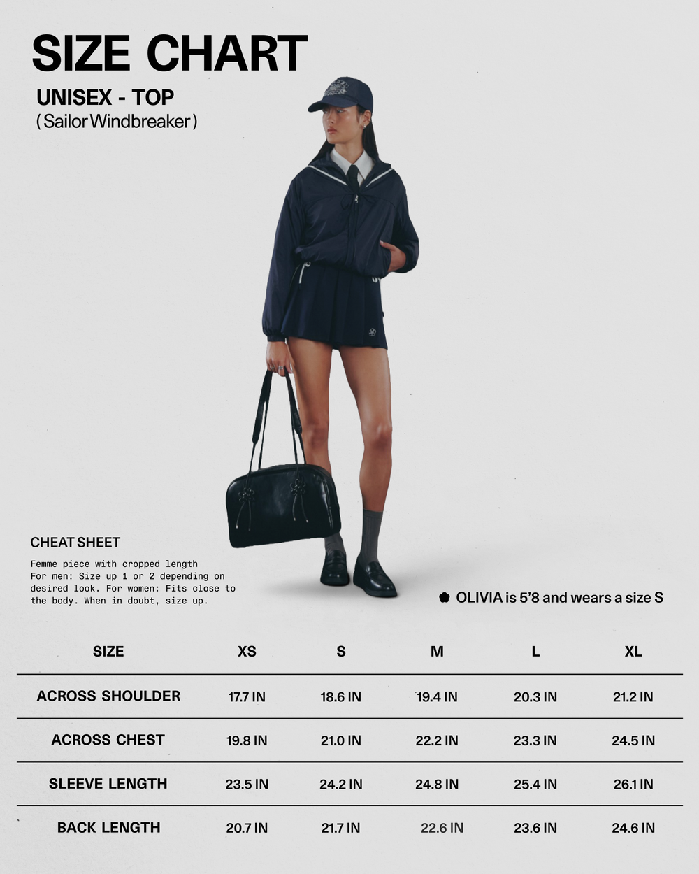 A woman stands holding a black bag, dressed in the Sundae School NAVY SAILOR WINDBREAKER, paired with a white shirt, navy skirt, sailor hat, and black shoes. A size chart and measurements for the unisex NAVY SAILOR WINDBREAKER are displayed beside her.