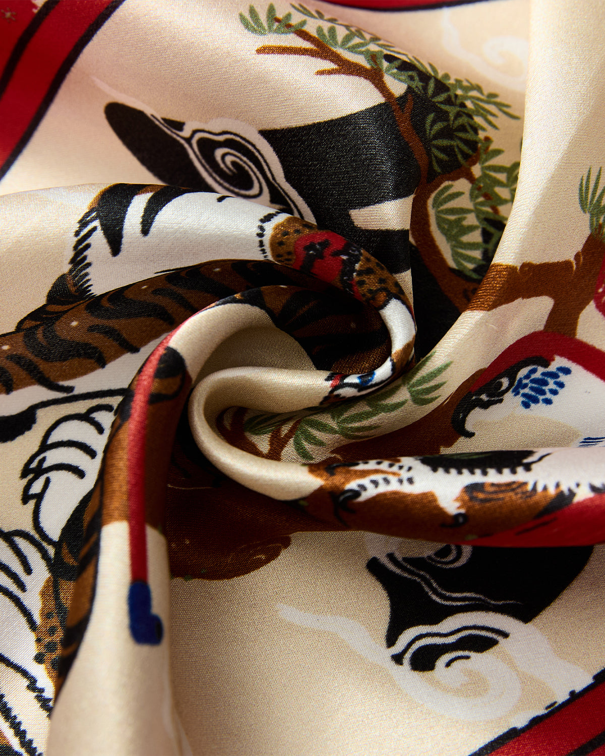 Close-up of the MINHWA BANDANA by Sundae School—a luxurious silk scarf with vibrant animal motifs inspired by Korean folk art, featuring birds and a tiger amid branches on a cream background with colorful accents.
