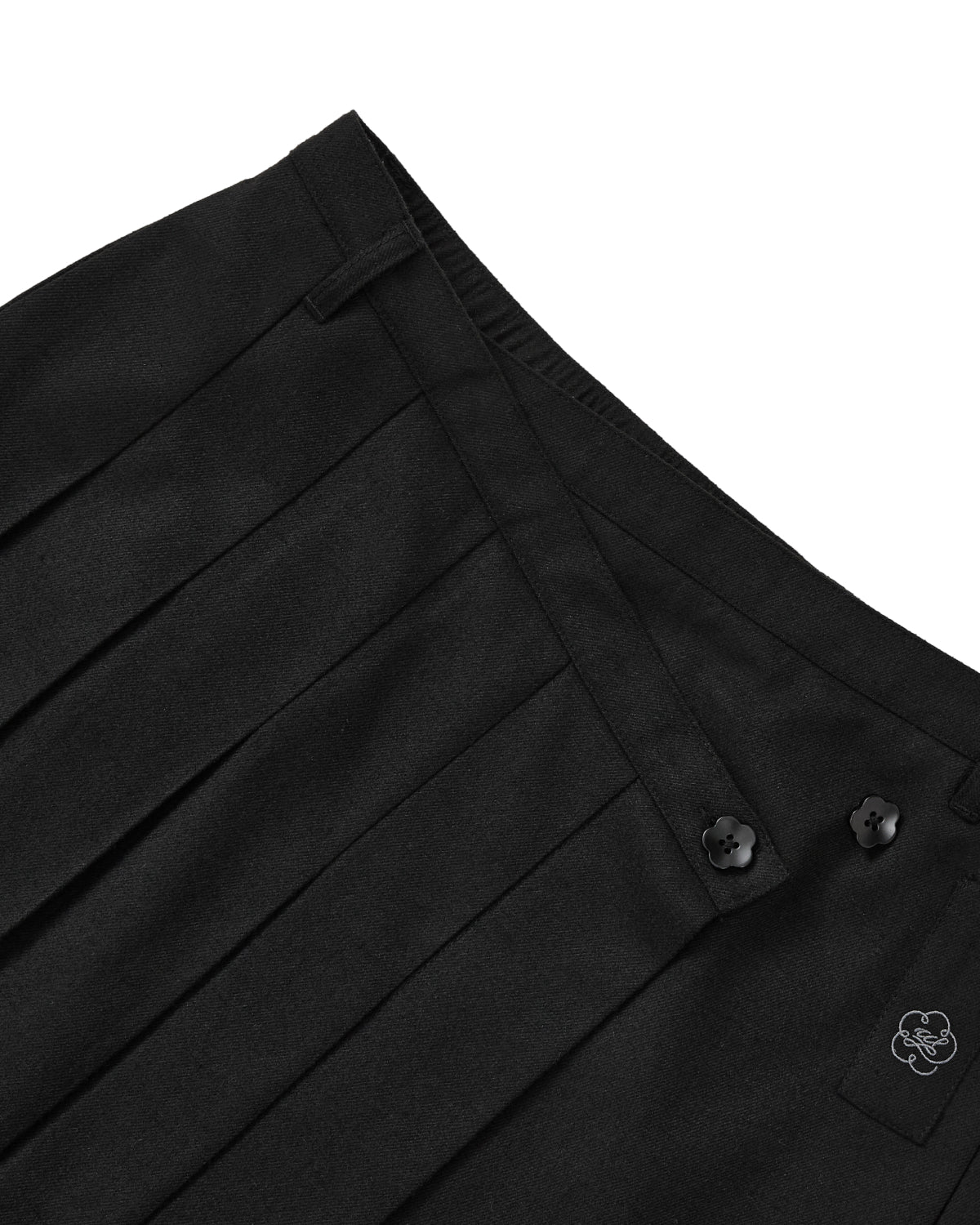 Sundae School BLACK MOON WRAP MIDI SKIRT: a black asymmetric pleated midi skirt with two flower-shaped waist buttons and a small embroidered emblem on the lower front.