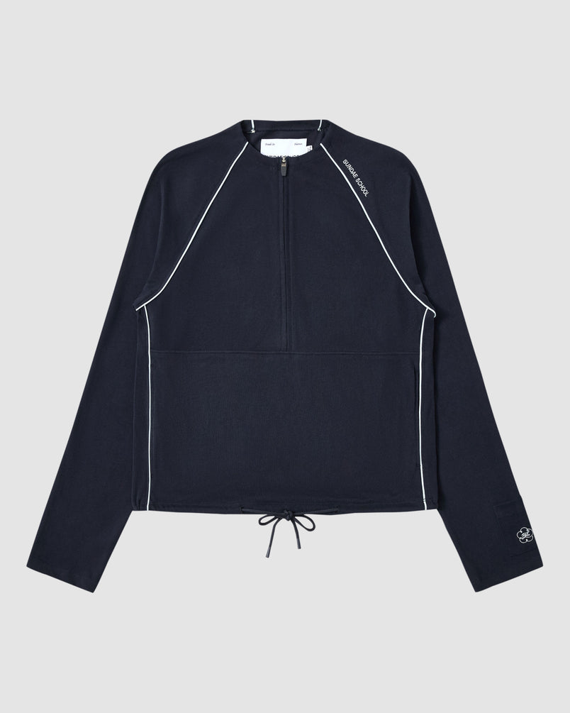 The NAVY OFFICE QUARTER ZIP by Sundae School is a navy cotton jersey long-sleeve pullover featuring white piping, a quarter-zip front, drawstring hem, stash pocket, and subtle white logos on the collar and sleeve. Displayed flat on light gray.
