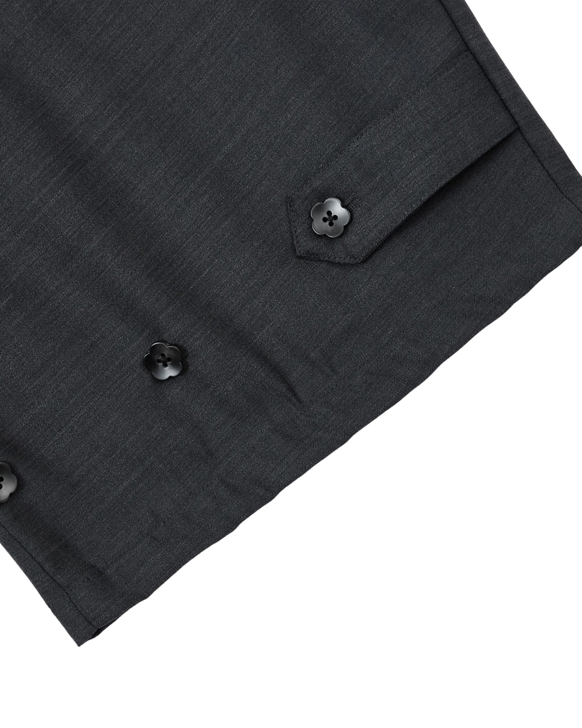 Close-up of a dark gray wool fabric, likely part of a suit jacket, featuring three black buttons and a small pocket with a buttoned flap on the right side. This refined detail pairs effortlessly with Sundae School’s CHARCOAL PLEATED HANBOK SLACKS for a contemporary yet classic look.