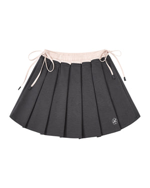 CHARCOAL PLEATED JERSEY MINI SKIRT by Sundae School: A charcoal gray knife-pleated mini skirt with a light pink waistband and matching drawstrings, finished with a small white embroidered flower logo near the hem.