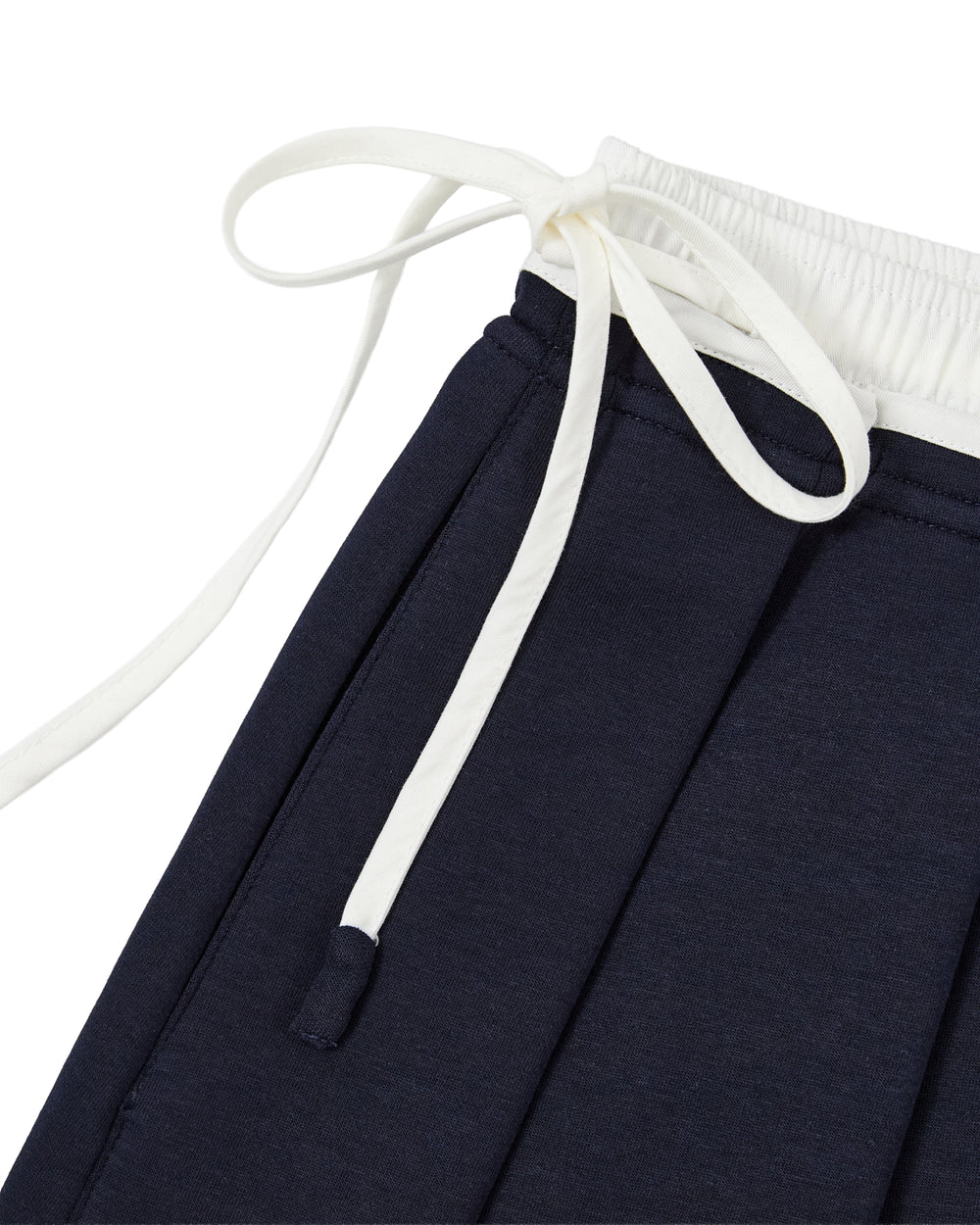 Close-up of the NAVY PLEATED JERSEY MINI SKIRT by Sundae School, featuring a navy blue cotton blend with an elastic white waistband and white drawstrings tied in a bow, designed for a comfortable fit.