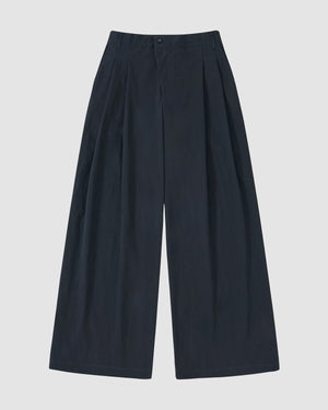 The Sundae School NAVY PLEATED UNIFORM SLACKS feature a high-waisted, wide-leg design with front pleats and side pockets, inspired by modern Korean gyobok and photographed laid flat on a plain light background.