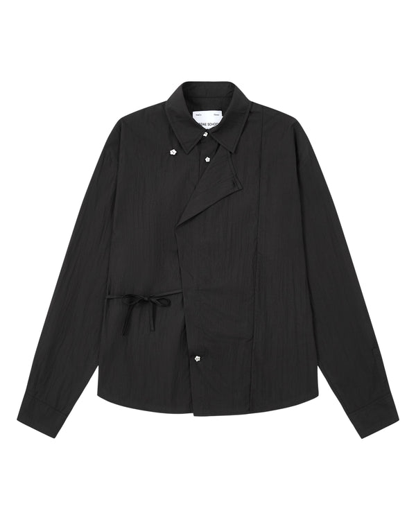 Introducing the BLACK POPLIN TIE GORUM SHIRT by Sundae School: a black long-sleeve, unisex tailored-fit shirt crafted from crisp cotton-nylon poplin. Featuring a unique asymmetric front with snap buttons and side tie detail, this modern yet timeless piece is laid flat against a white background, blending contemporary design with lasting comfort.