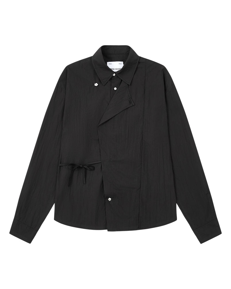 Introducing the BLACK POPLIN TIE GORUM SHIRT by Sundae School: a black long-sleeve, unisex tailored-fit shirt crafted from crisp cotton-nylon poplin. Featuring a unique asymmetric front with snap buttons and side tie detail, this modern yet timeless piece is laid flat against a white background, blending contemporary design with lasting comfort.