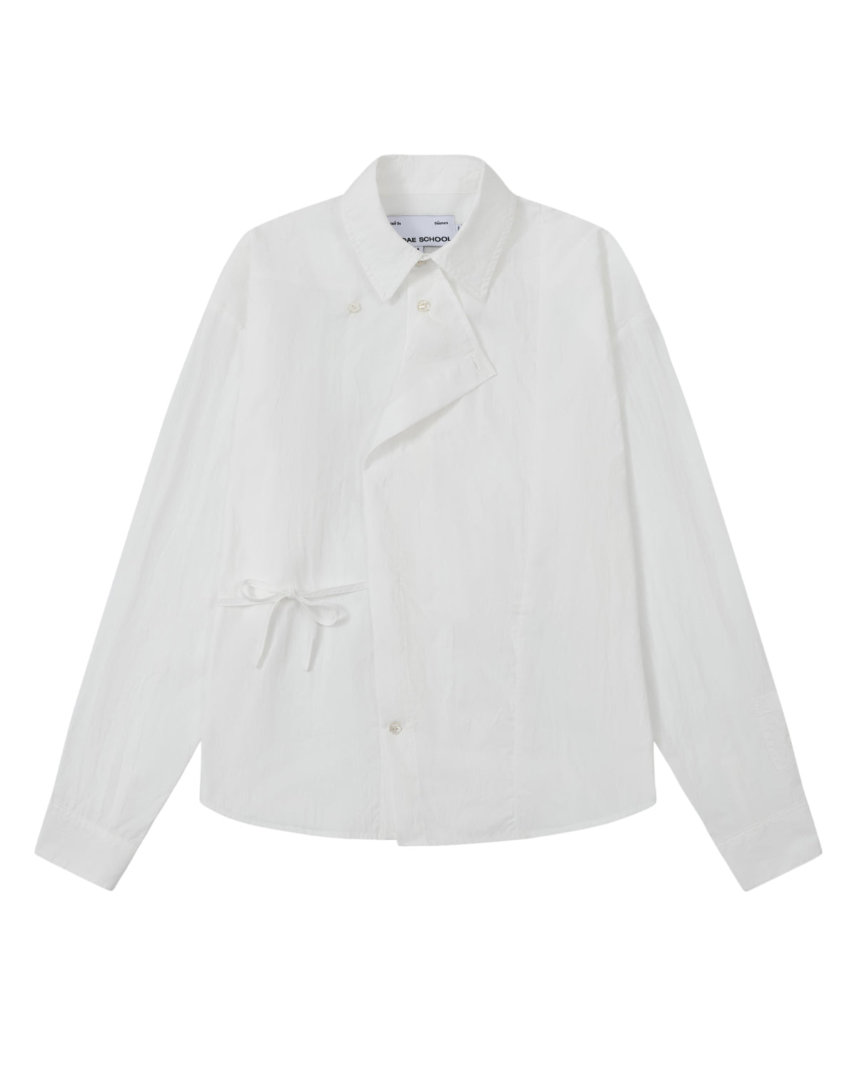 The WHITE POPLIN TIE GORUM SHIRT by Sundae School is a unisex, tailored-fit white long-sleeve shirt crafted from cotton nylon poplin. It features an asymmetrical front, classic collar, and distinctive side tie detail, with a double-layered front panel adding dimension. Shown on a plain background.