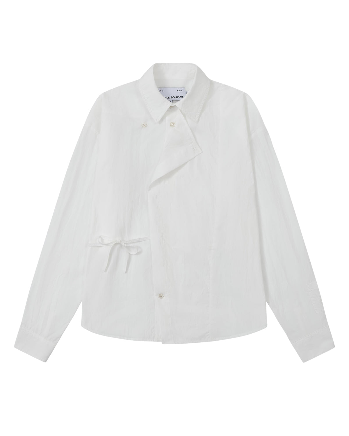 A front flat-lay view of an off-white long-sleeve button-up shirt crafted from textured crinkle fabric. It features an asymmetrical wrap-front construction with a side waist tie, a pointed collar, and flower-shaped button details.