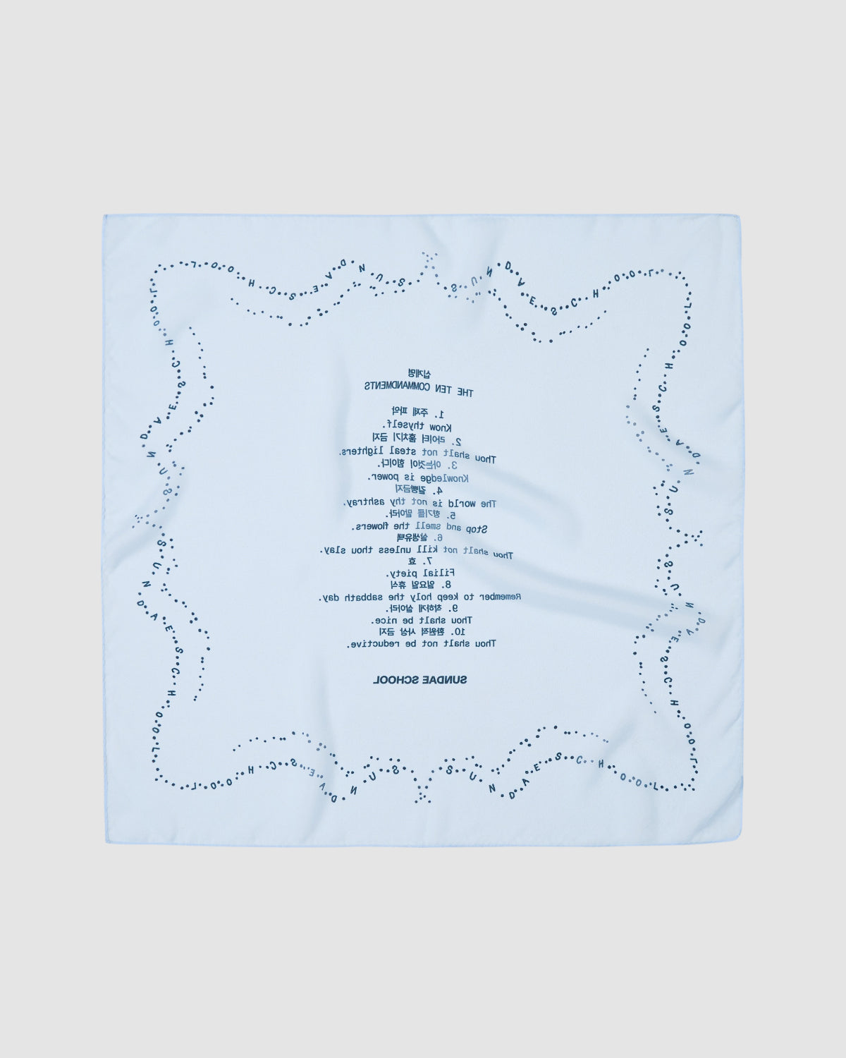 The SKY BLUE 10 COMMANDMENTS ORGANZA BANDANA by Sundae School features light blue silk organza, a dotted border, and blue mirrored “Ten Commandments” text at the center, displayed on a plain light background.