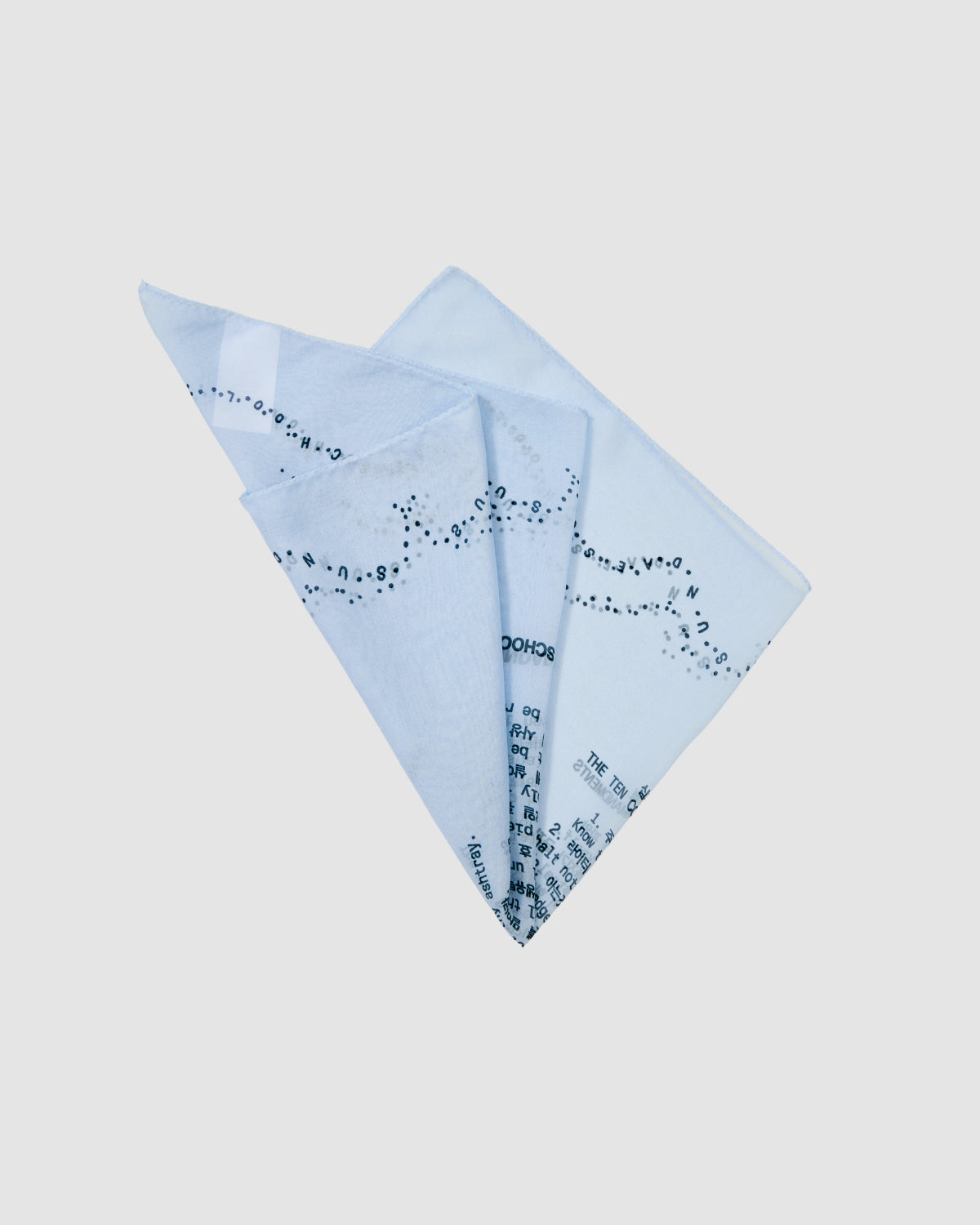 The SKY BLUE 10 COMMANDMENTS ORGANZA BANDANA by Sundae School is a folded sheer square scarf in light blue with scattered black text, inspired by the brand’s Ten Commandments, shown on a plain white background.