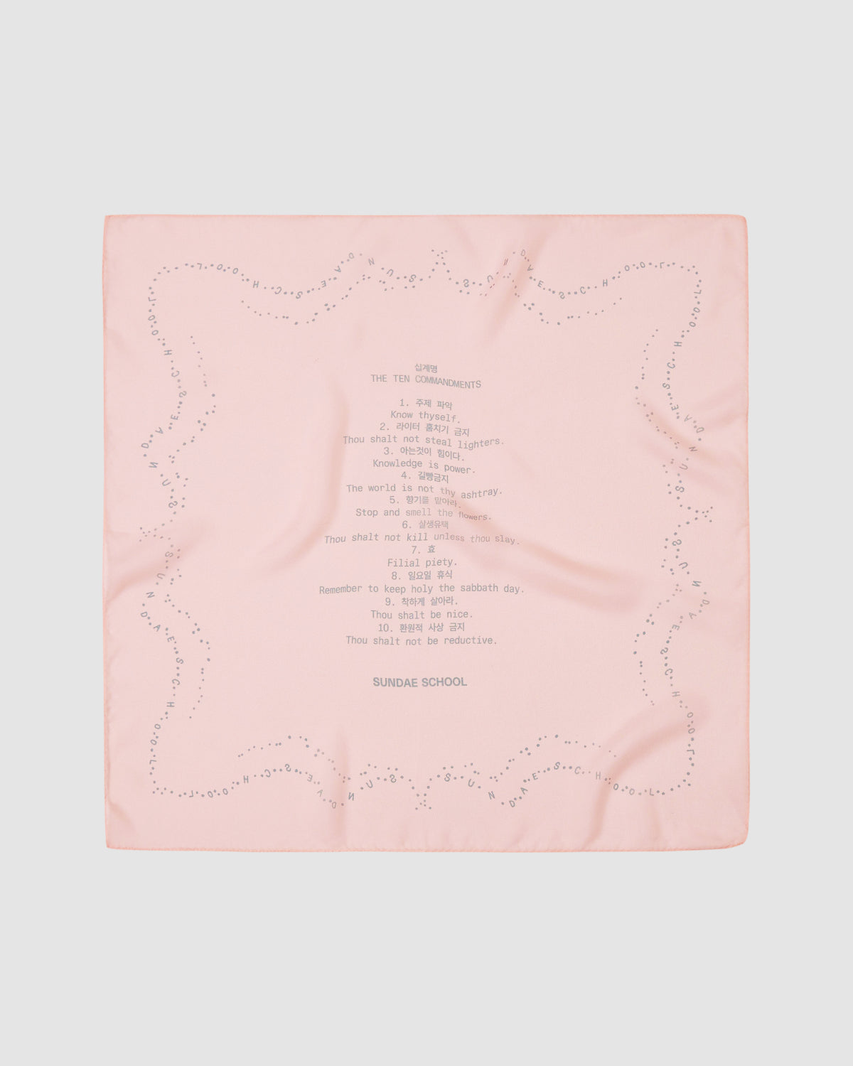 The BABY PINK 10 COMMANDMENTS ORGANZA BANDANA by Sundae School is a pale pink silk bandana with a dotted border, Ten Commandments print at the center, and 