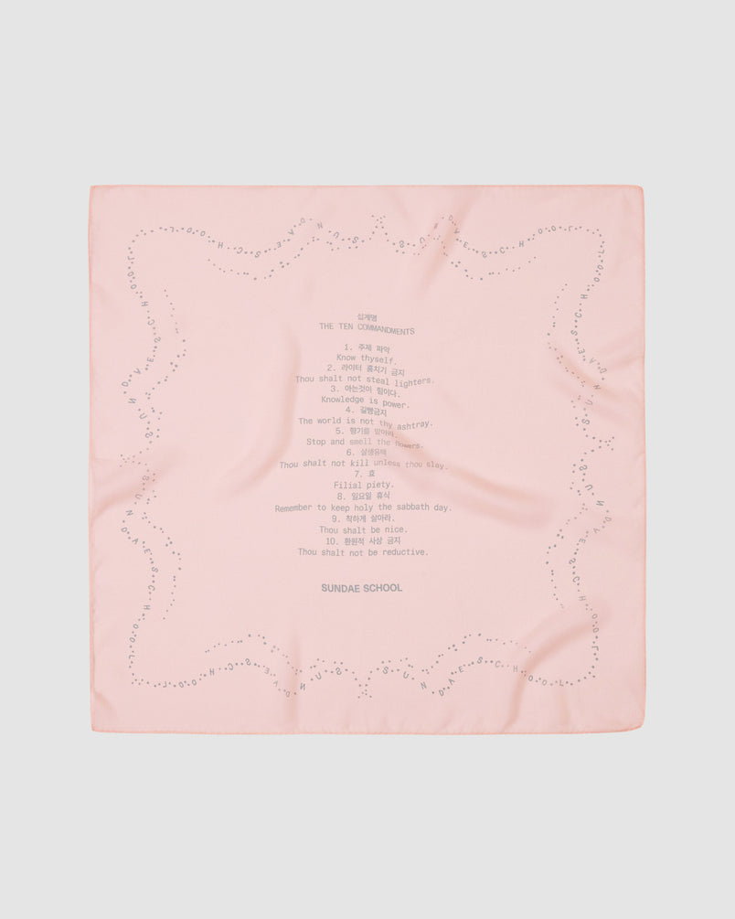 The BABY PINK 10 COMMANDMENTS ORGANZA BANDANA by Sundae School is a pale pink silk bandana with a dotted border, Ten Commandments print at the center, and "SUNDAE SCHOOL" beneath it on a light gray background.