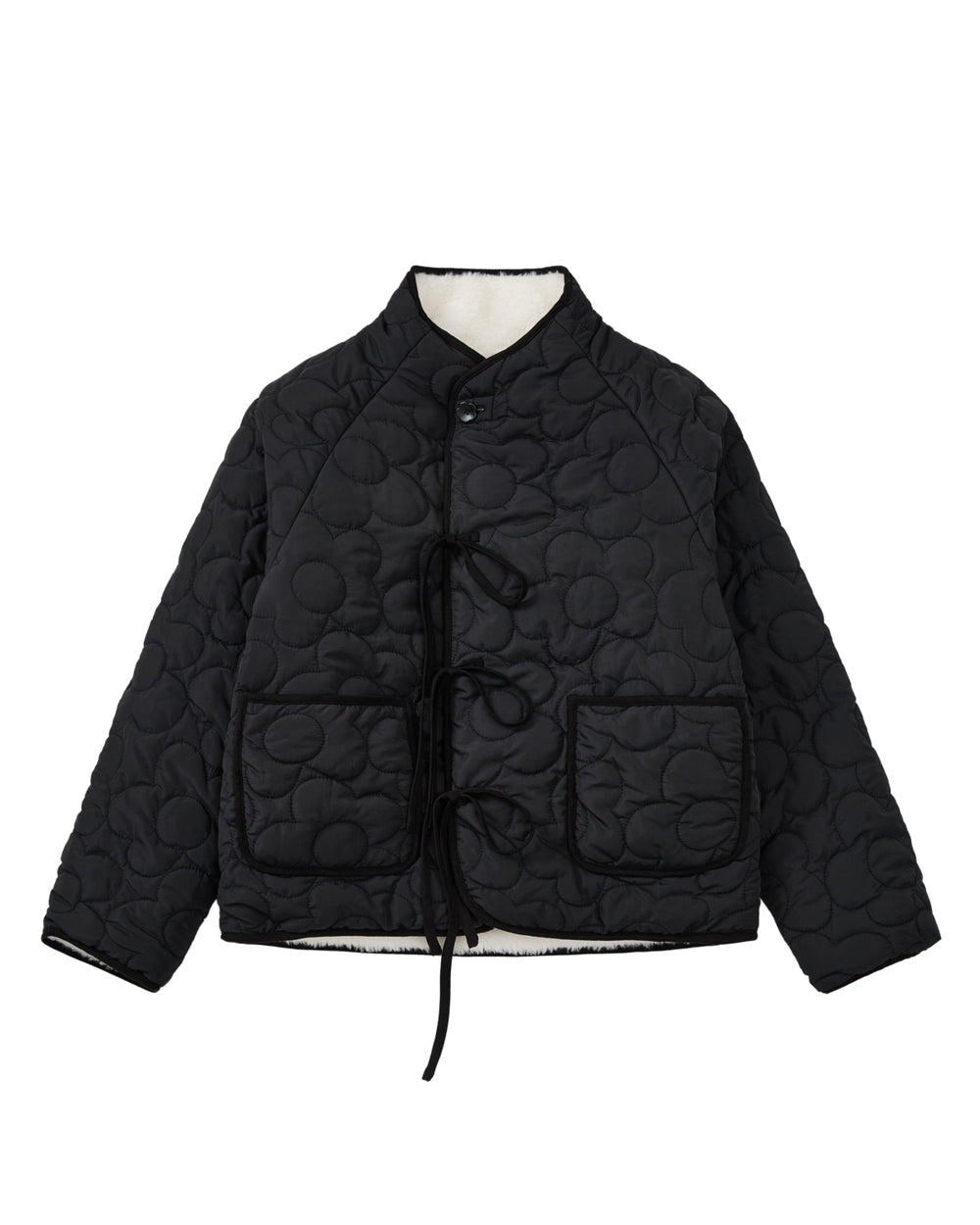 The BLACK IVORY REVERSIBLE FLOWER QUILTED JEOGORI FLEECE by Sundae School features a reversible floral quilted design, front tie closures, two spacious front pockets, and a high collar, shown against a white background.