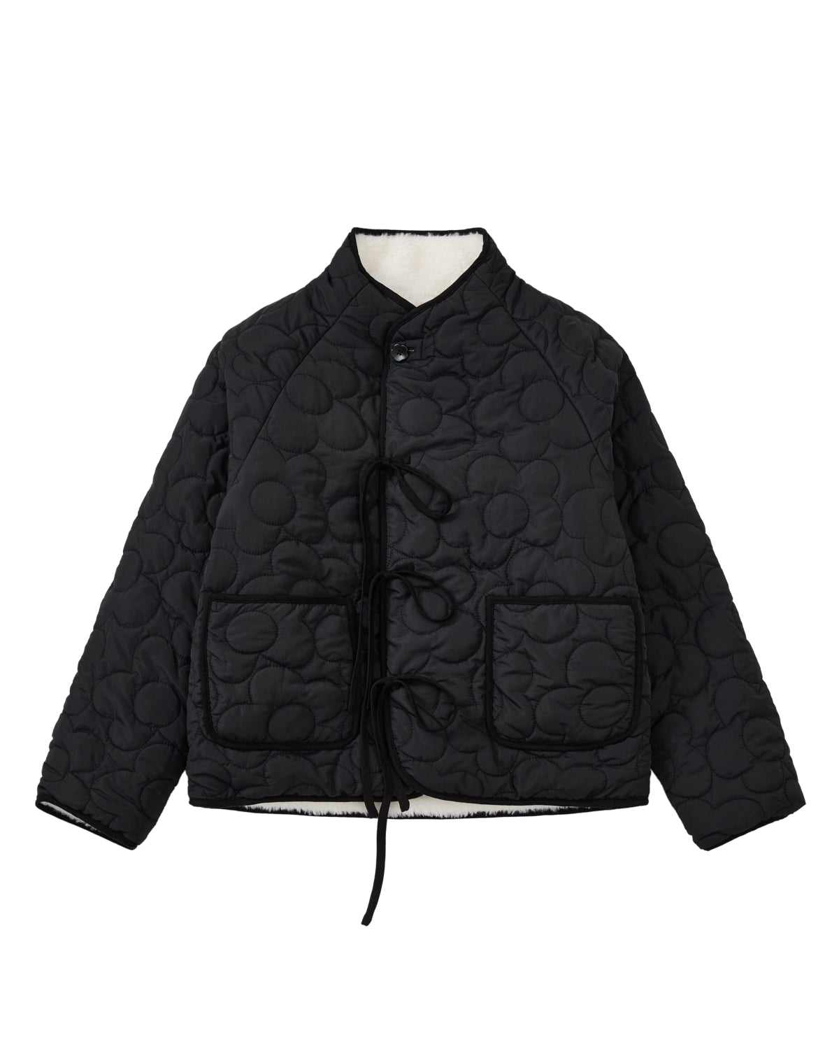 The BLACK IVORY REVERSIBLE FLOWER QUILTED JEOGORI FLEECE by Sundae School features a reversible floral quilted design, front tie closures, two spacious front pockets, and a high collar, shown against a white background.