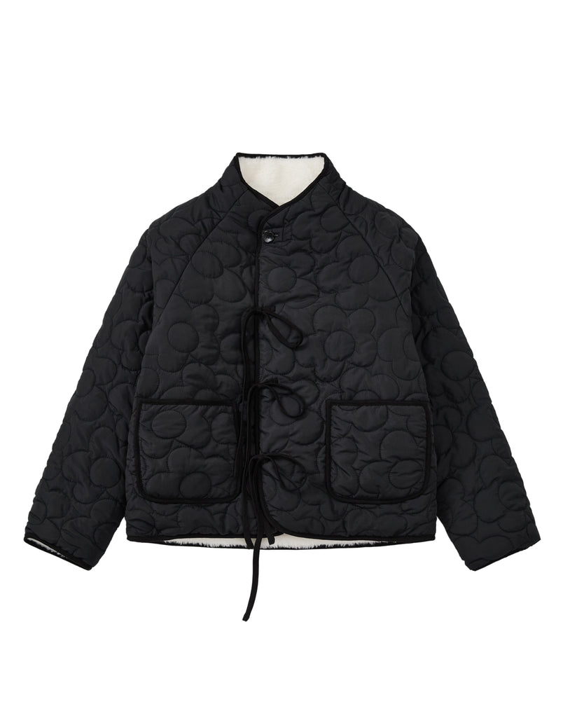 The BLACK IVORY REVERSIBLE FLOWER QUILTED JEOGORI FLEECE by Sundae School features a reversible floral quilted design, front tie closures, two spacious front pockets, and a high collar, shown against a white background.