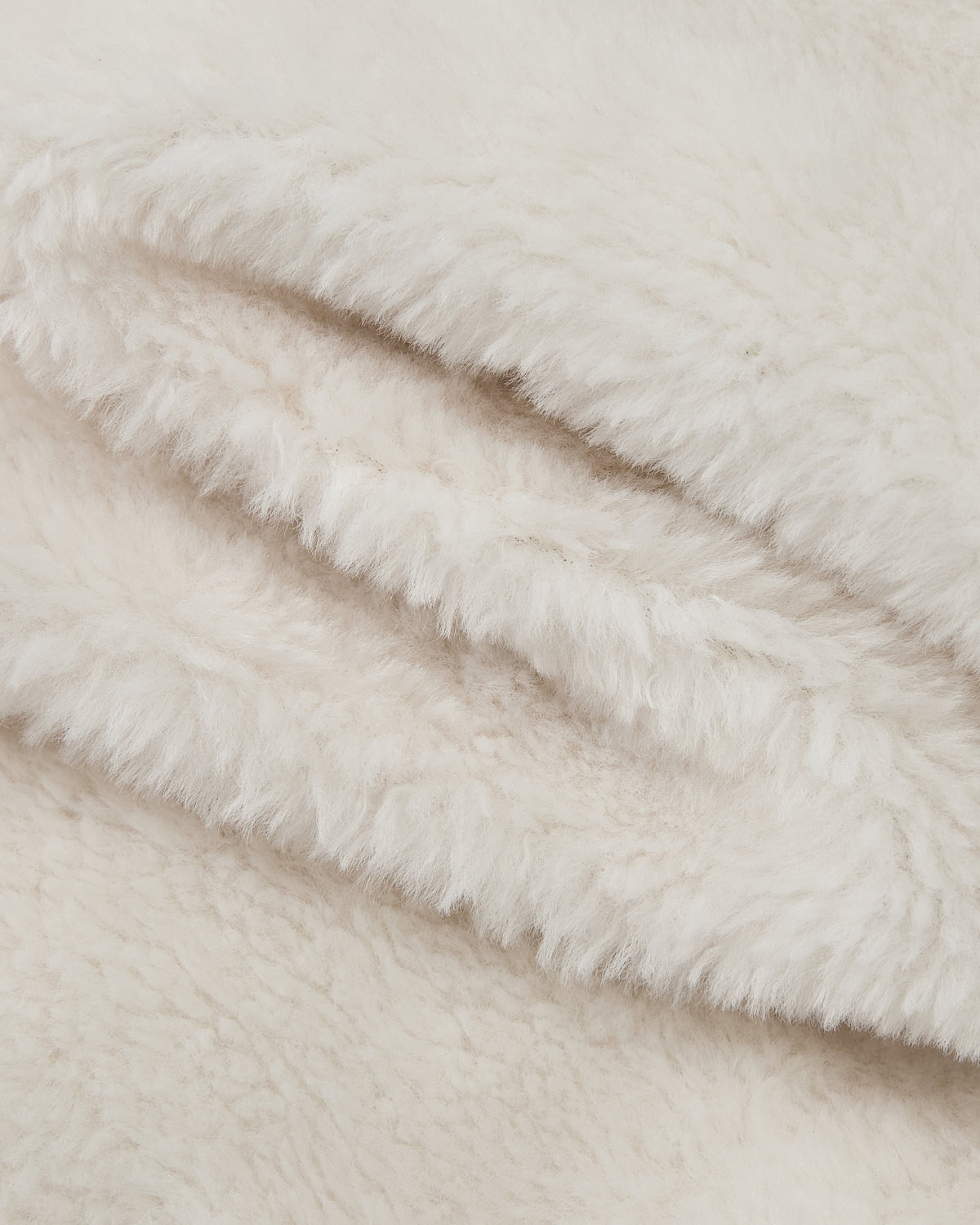 Close-up of the BLACK IVORY REVERSIBLE FLOWER QUILTED JEOGORI FLEECE by Sundae School—soft, off-white faux fur fabric displaying fluffy, textured fibers and gentle folds, ideal for this cozy hanbok-inspired coat.
