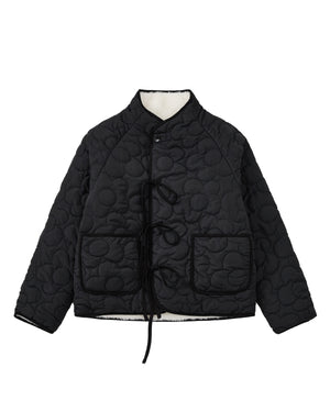 The BLACK IVORY REVERSIBLE FLOWER QUILTED JEOGORI FLEECE by Sundae School features a reversible floral quilted design, front tie closures, two spacious front pockets, and a high collar, shown against a white background.