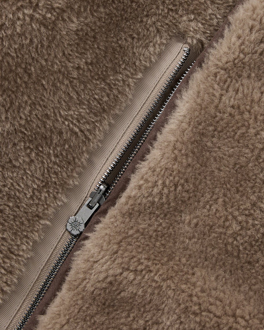 Close-up of the khaki, faux-sherpa fleece fabric with a visible silver zipper partially unzipped, highlighting the soft texture and intricate stitching details of the Sundae School KHAKI REVERSIBLE FLOWER QUILTED JEOGORI FLEECE.