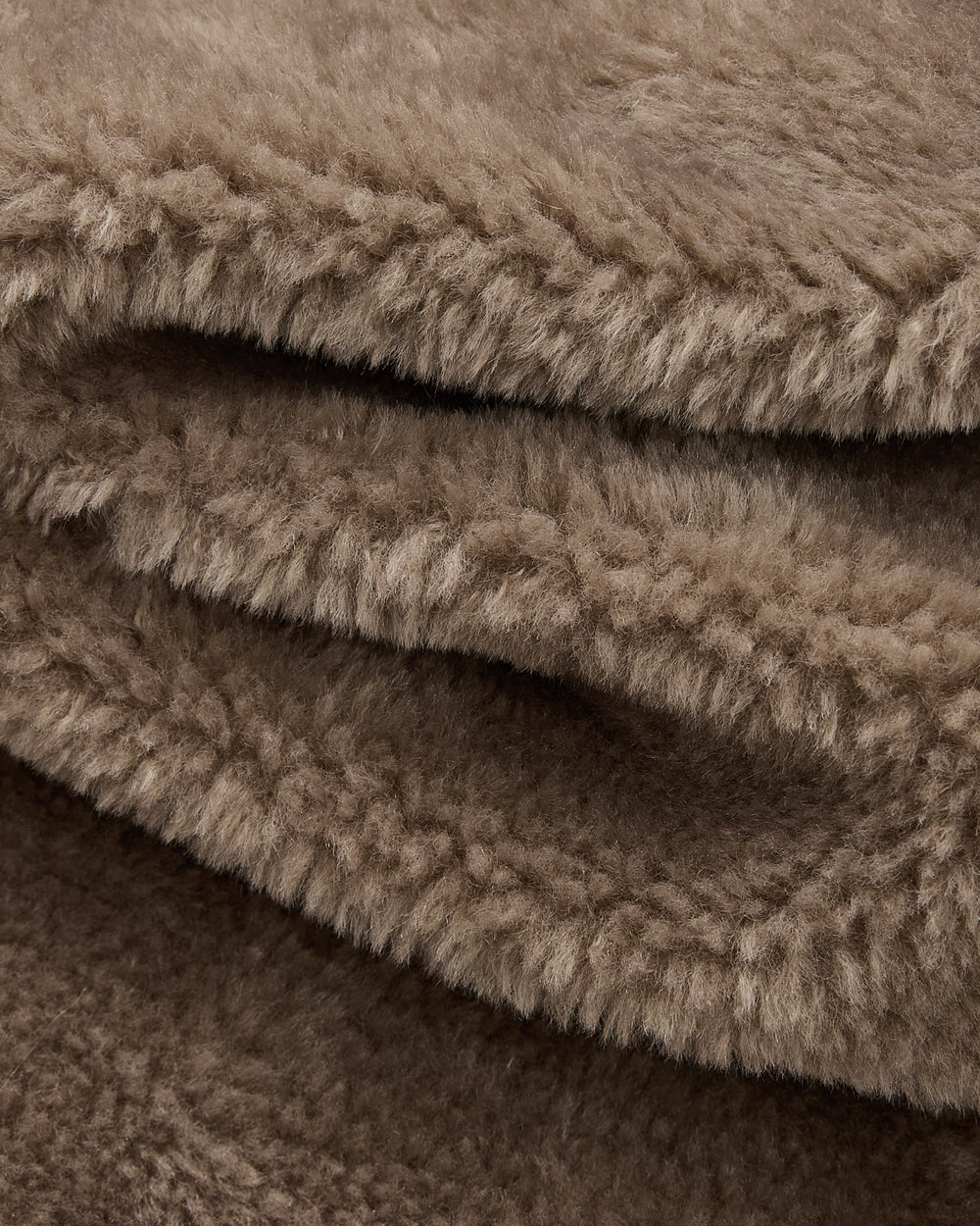 Close-up of the KHAKI REVERSIBLE FLOWER QUILTED JEOGORI FLEECE by Sundae School, featuring light brown, soft, and fluffy fabric with a thick, fuzzy texture—evoking the plush comfort of faux-sherpa puffer material—artfully folded in gentle layers.