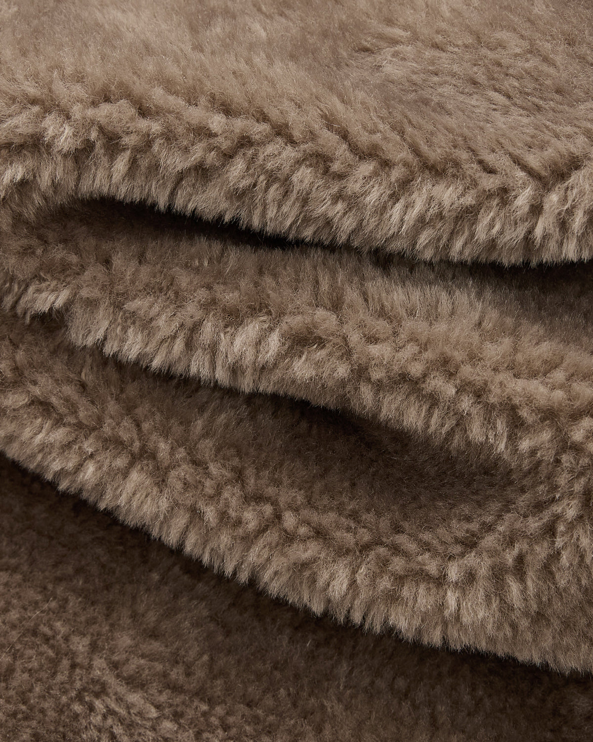 Close-up of the KHAKI REVERSIBLE FLOWER QUILTED JEOGORI FLEECE by Sundae School, featuring light brown, soft, and fluffy fabric with a thick, fuzzy texture—evoking the plush comfort of faux-sherpa puffer material—artfully folded in gentle layers.