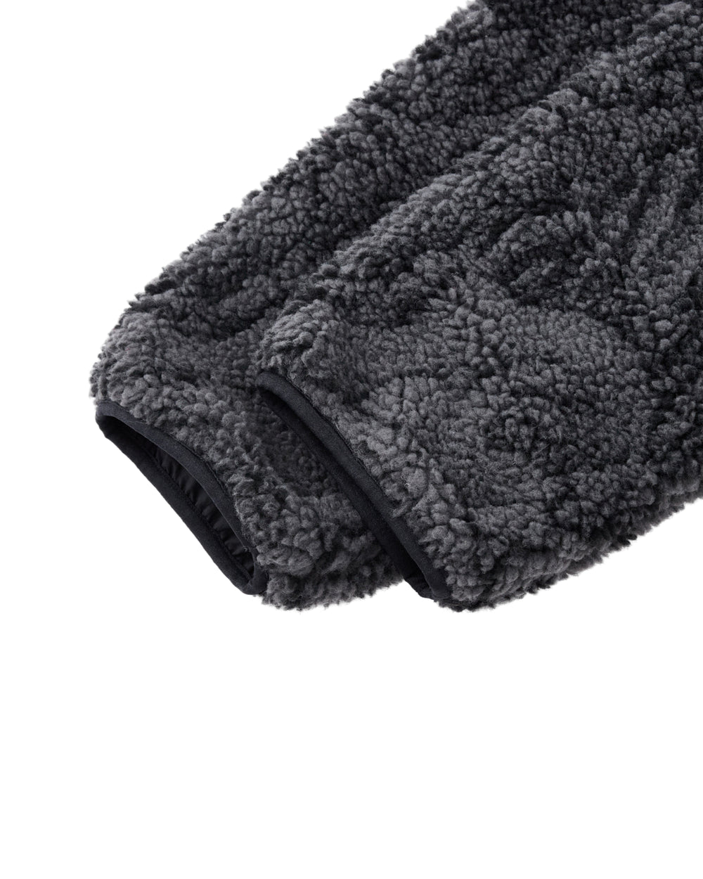 Close-up of the BLACK REVERSIBLE IREZUMI FLEECE by Sundae School, featuring a gray, textured jacquard sleeve with black trim at the cuff and showcasing its soft, plush material.