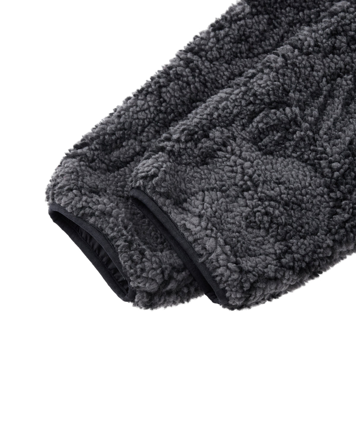 Close-up of the BLACK REVERSIBLE IREZUMI FLEECE by Sundae School, featuring a gray, textured jacquard sleeve with black trim at the cuff and showcasing its soft, plush material.