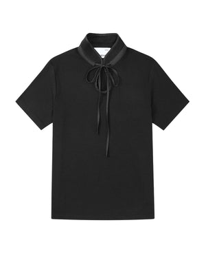 The BLACK RIBBON TIE POLO by Sundae School is a short-sleeve polo featuring a high Manchurian teardrop collar and a black ribbon tied in a bow at the neck, shown laid flat on a white background.