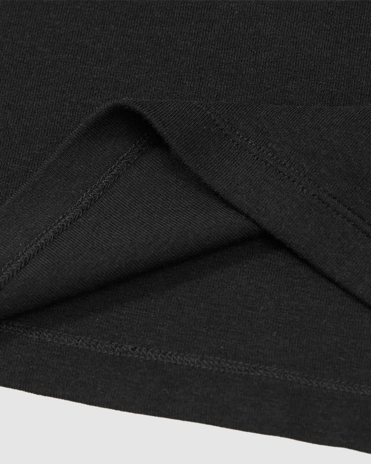 Close-up of the hem and stitching on the Sundae School BLACK RIBBON TIE POLO, highlighting the smooth black fabric and subtle Korean goreum detail along the inner seam.