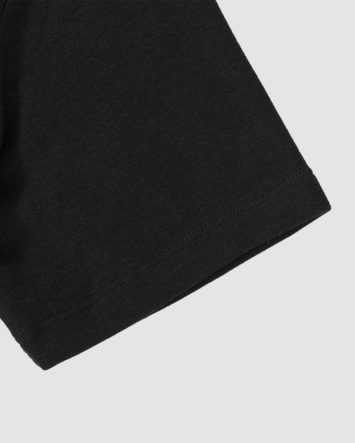Close-up of the hem on Sundae School's BLACK RIBBON TIE POLO shows a subtle Korean goreum detail against a plain light gray background.