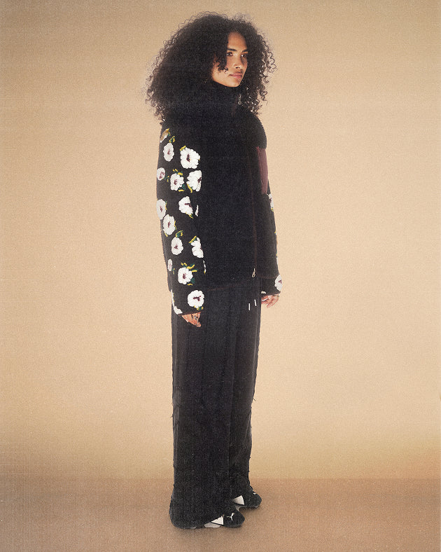 A female model wearing Sundae School Black Mugunghwa Fleece against a brown background.