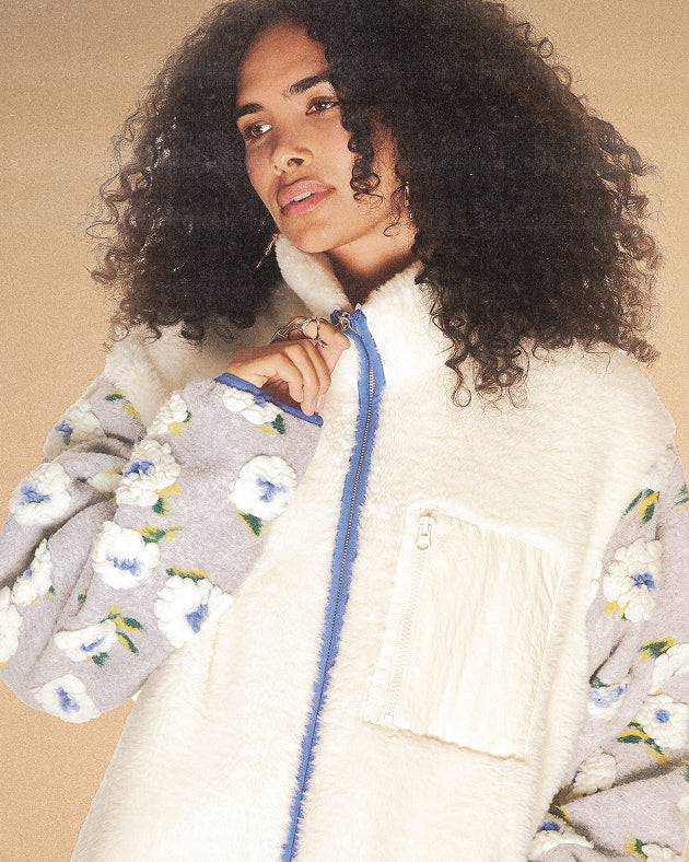 A female girl wearing Ivory Mugunghwa Fleece against a brown background.
