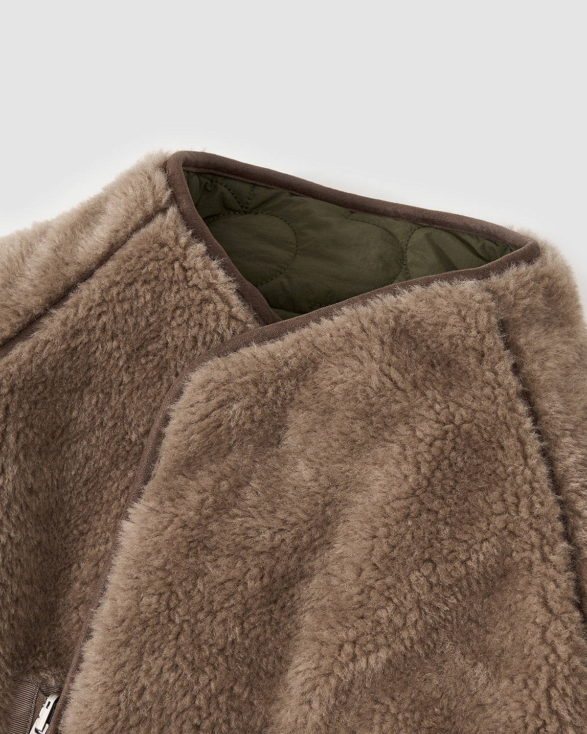 Close-up of Sundae School’s [PRE-ORDER] REVERSIBLE FLOWER QUILTED JEOGORI FLEECE in brown teddy sherpa with olive green quilted lining and an asymmetric zipper, against a plain light gray background.