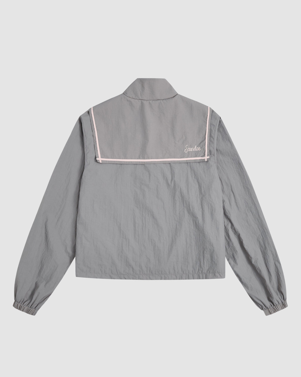 The CHARCOAL SAILOR WINDBREAKER by Sundae School is a light gray, cropped jacket with pink piping, elastic cuffs, long sleeves, and 