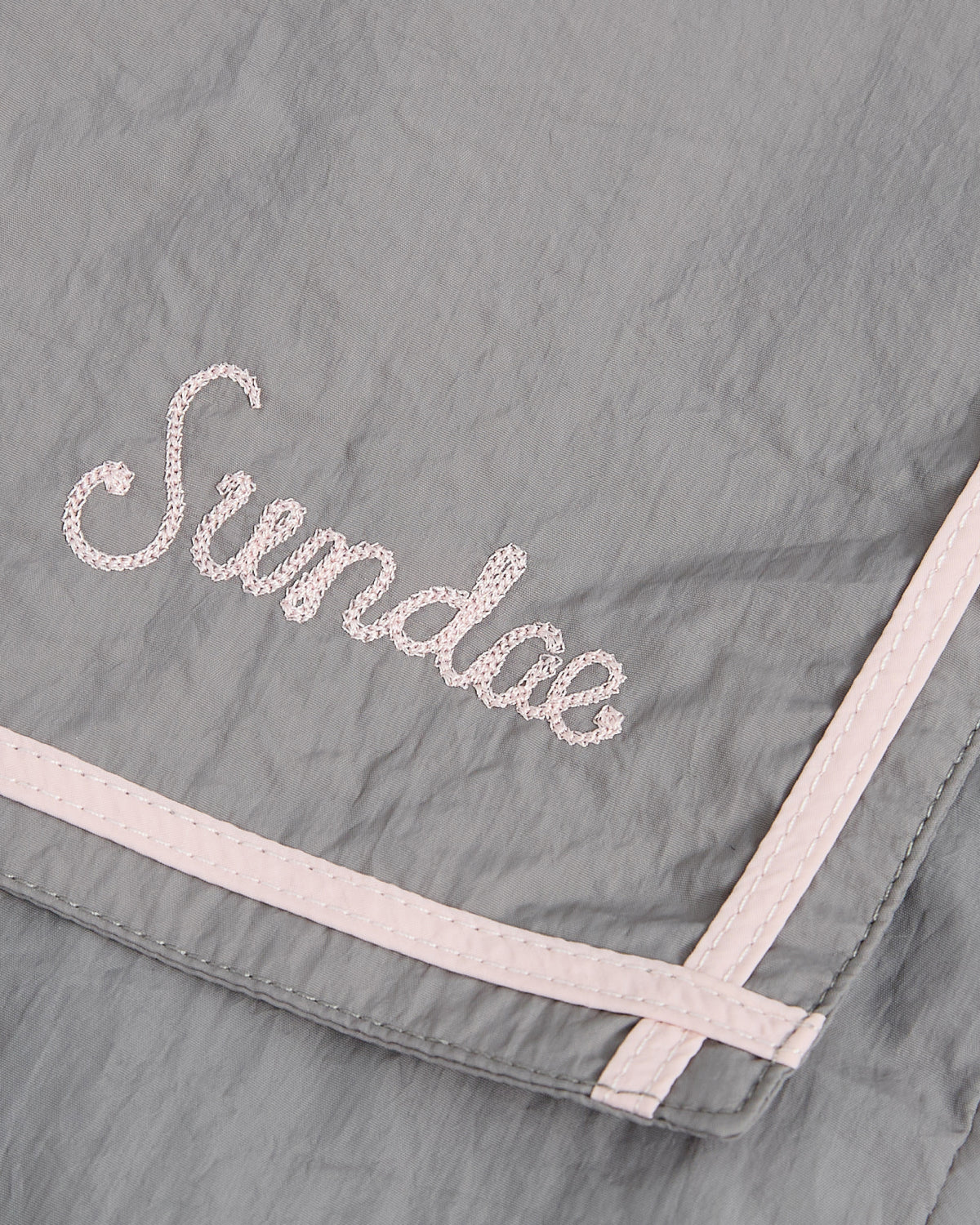 The CHARCOAL SAILOR WINDBREAKER by Sundae School features gray fabric with light pink trim, a cropped silhouette, and 