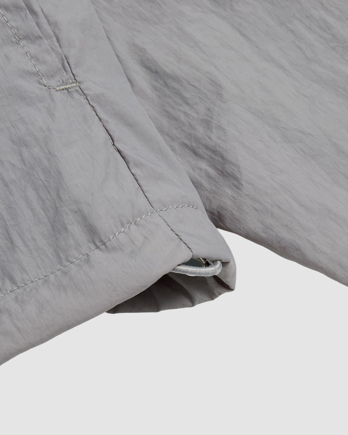 Close-up of the hem and sleeve of the Sundae School CHARCOAL SAILOR WINDBREAKER, highlighting visible stitching, a small opening at the cuff, and soft, slightly wrinkled fabric.