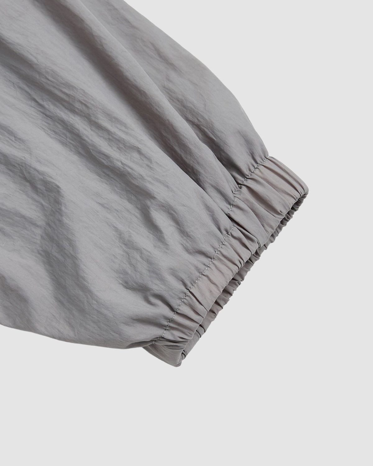 Close-up of the sleeve on Sundae School’s CHARCOAL SAILOR WINDBREAKER, showing a gathered elastic cuff against a white background. The lightweight fabric has a slightly crinkled texture.