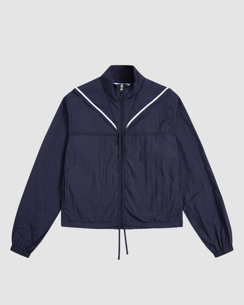 The Sundae School NAVY SAILOR WINDBREAKER is a navy cropped jacket with a high collar, long sleeves, elastic cuffs, and V-shaped white piping on the chest, shown laid flat on a light gray background.