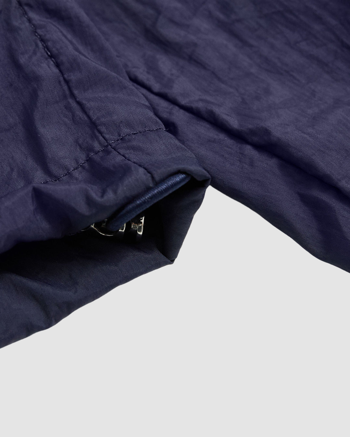 Close-up of the Sundae School NAVY SAILOR WINDBREAKER’s navy blue sleeve, with UV protection and a metal zipper, shown flat on a light grey background.