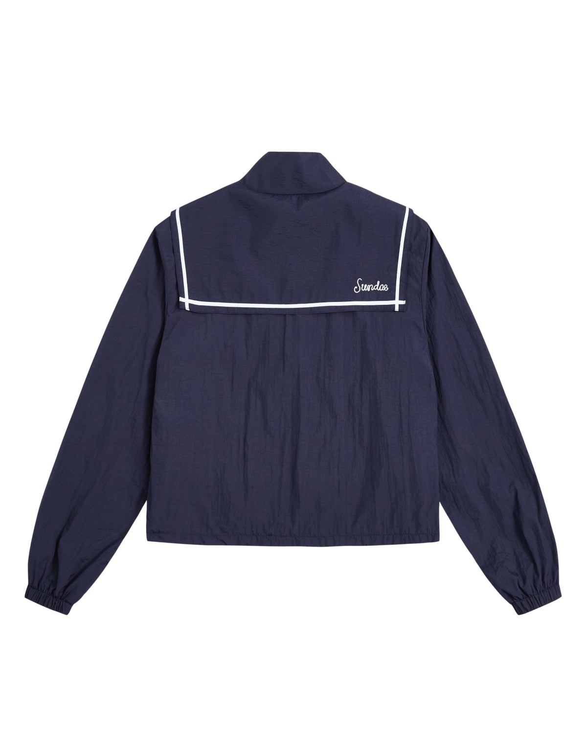 The NAVY SAILOR WINDBREAKER by Sundae School is a navy blue cropped windbreaker with white trim and detailing, inspired by a classic sailor uniform jacket. It features a sailor-style collar, long sleeves with elastic cuffs, a straight hem, and “Sandro” embroidered on the back.