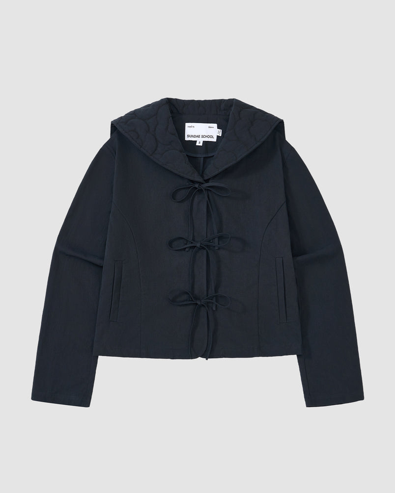 The NAVY SAILOR COLLAR UNIFORM JACKET by Sundae School features a dark navy hue, mochi quilted stitching, long sleeves, hood, front tie closures, two vertical pockets, and an inner collar label, shown on a light gray background.