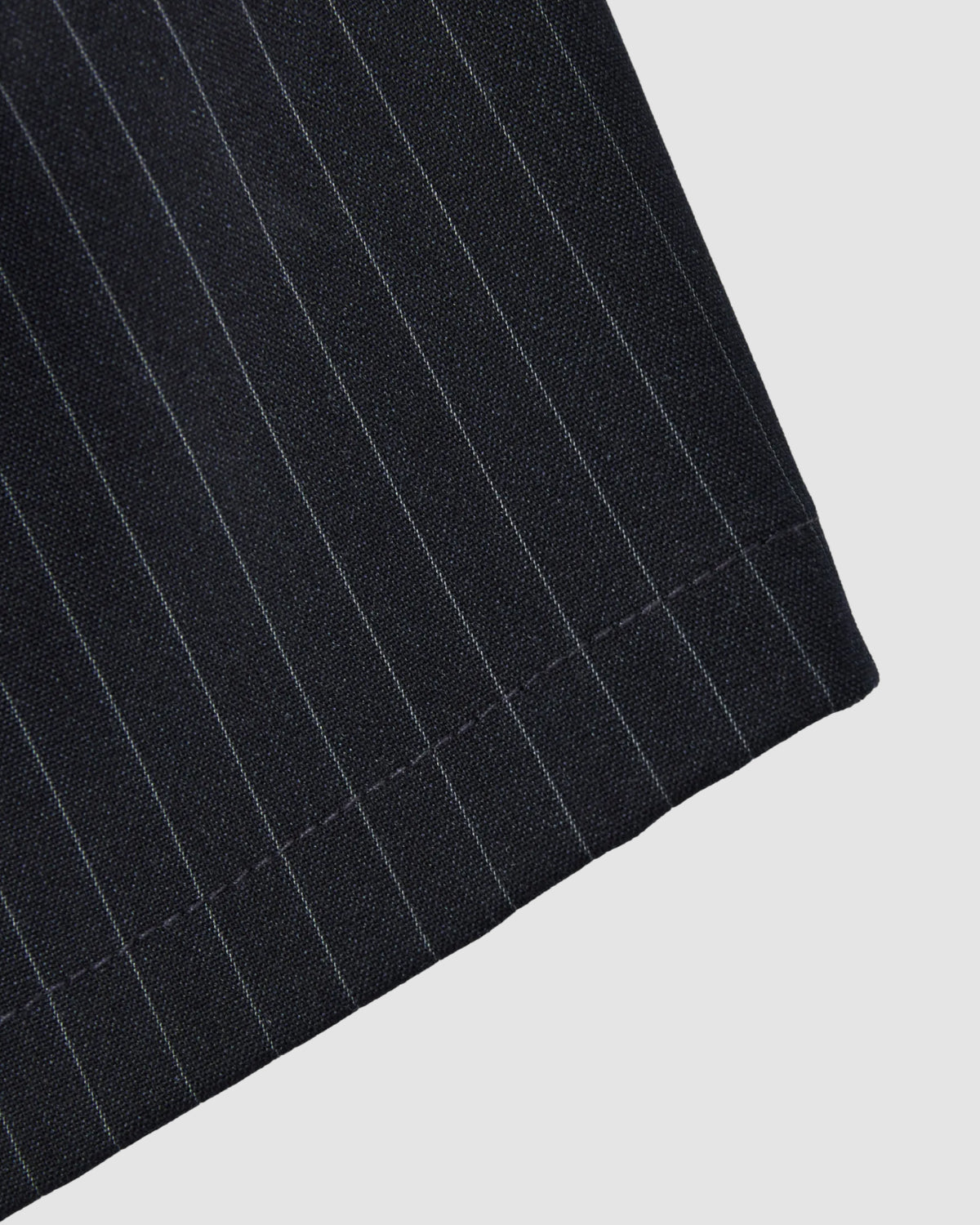 Close-up of Sundae School's NAVY STRIPE BOXER SHORTS featuring dark Tencel-rayon blend fabric with thin white pinstripes and a neatly sewn hem, photographed against a plain light background.